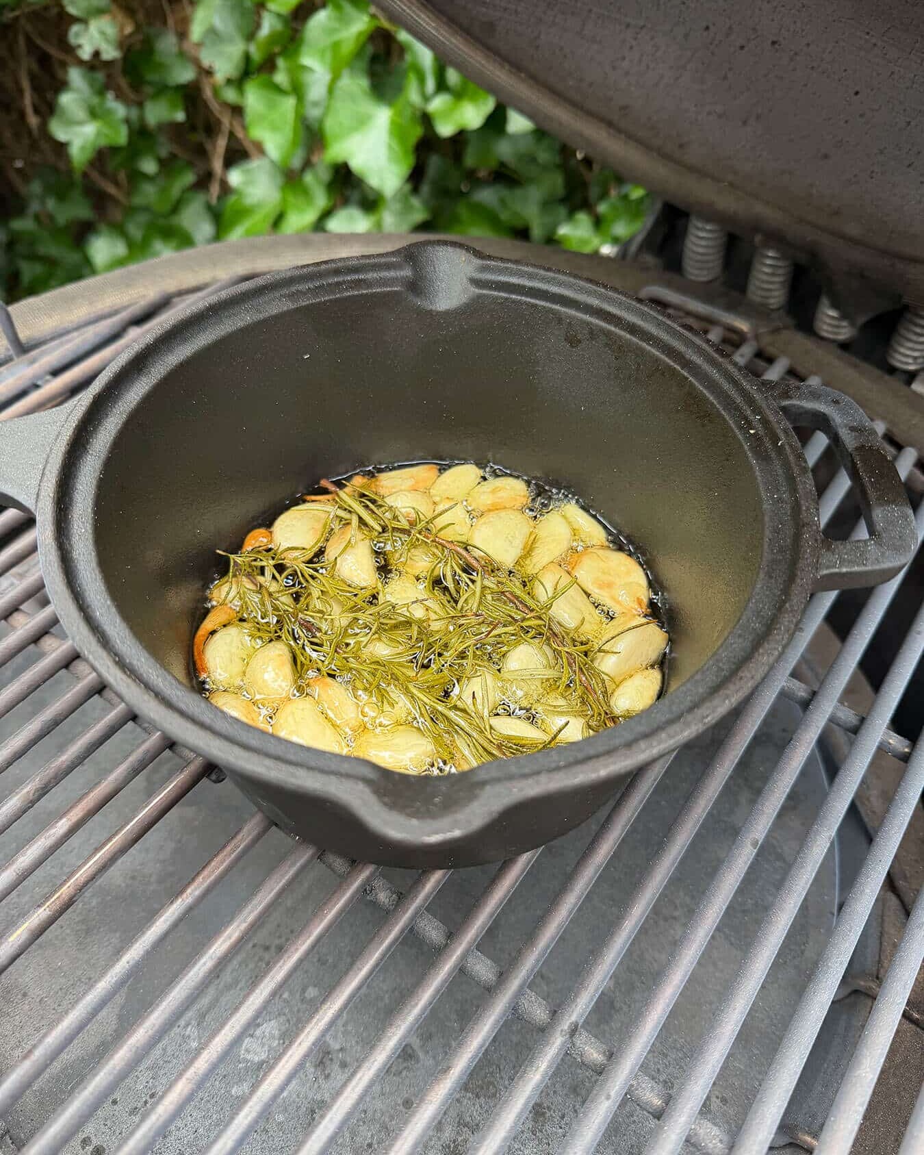 Gegrilde knoflook met rozemarijn in een gietijzeren pan op een barbecue - Dutch BBQ Dude