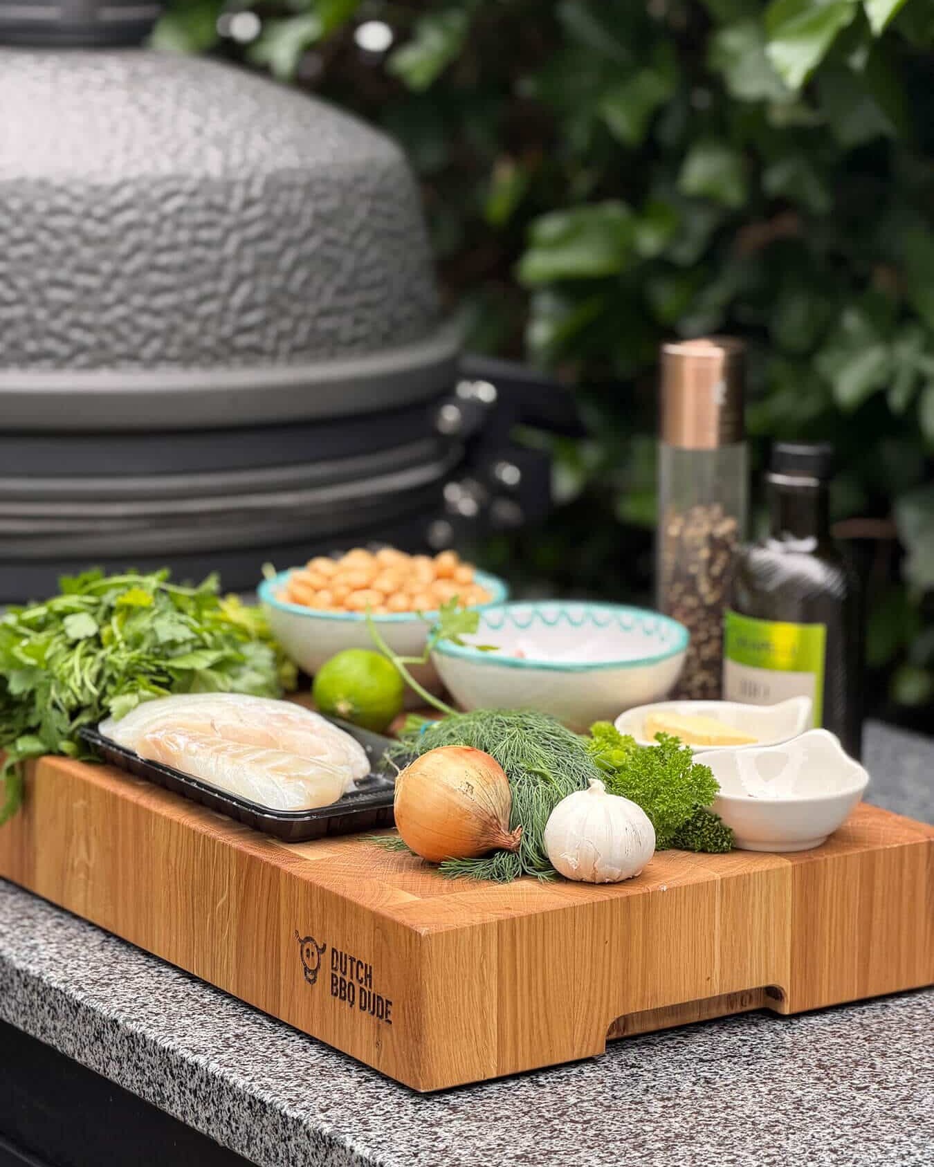 Ingrediënten voor een visgerecht op een houten snijplank, naast een barbecue - Dutch BBQ Dude